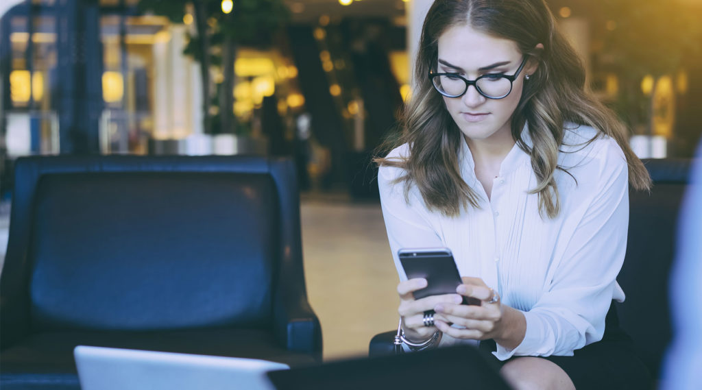 photo of young woman at job interview using her cellphone