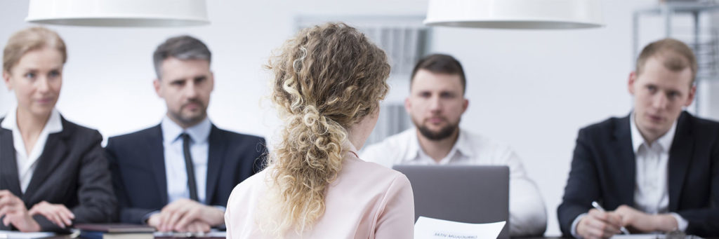 photo of a female job candidate being interviewed by a team of four business people in a company conference room