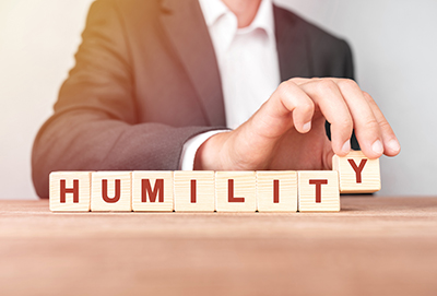 photo of businessman spelling out the word humility with blocks