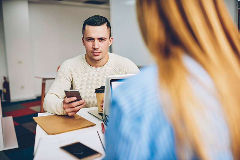 young businessperson texting on his iPhone during job interview