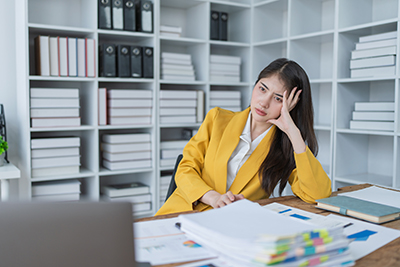 businesswoman sitting at her desk looking frustrated and bored